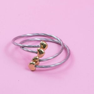 Stylish silver bracelets with gold accents on a pink surface. Perfect for adding luxury to your style.